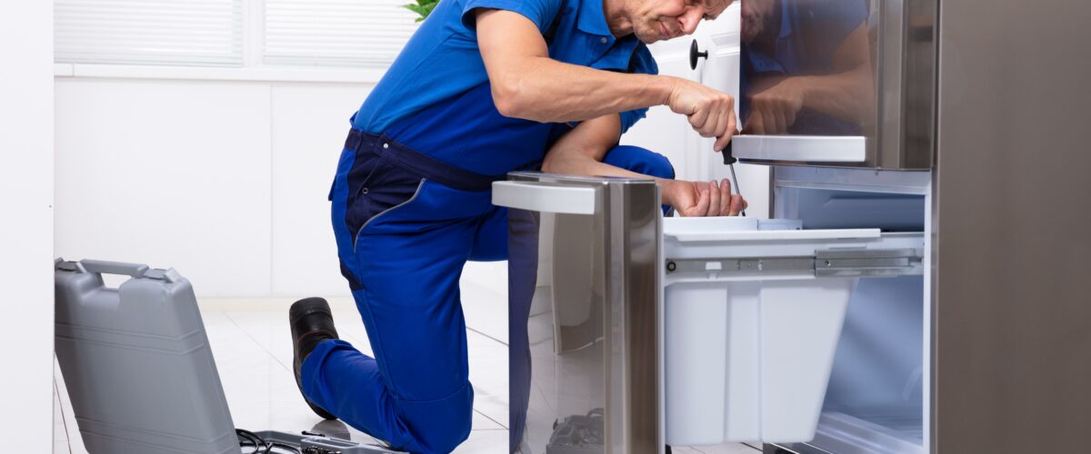 Teknisi memperbaiki kulkas dua pintu di rumah pelanggan