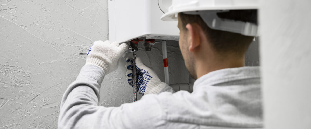 Teknisi sedang memperbaiki water heater di rumah pelanggan