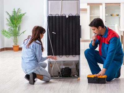 Teknisi memperbaiki kulkas di rumah pelanggan