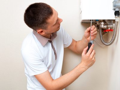 Teknisi sedang memperbaiki water heater di rumah pelanggan