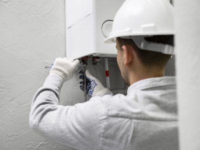 Teknisi sedang memperbaiki water heater di rumah pelanggan